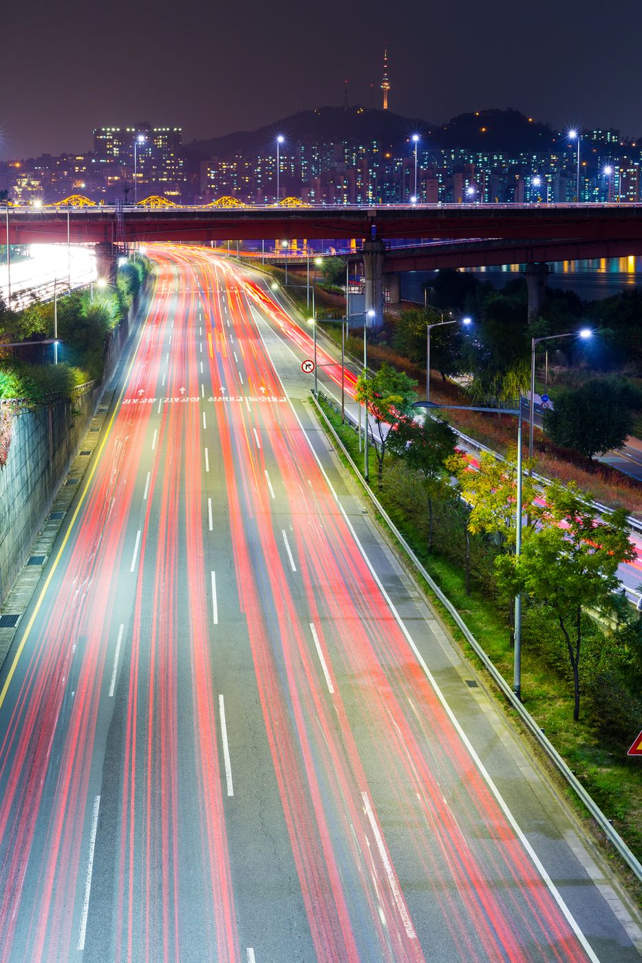 Speed limiter South Korea: night traffic light trails on a Seoul expressway below N Seoul Tower