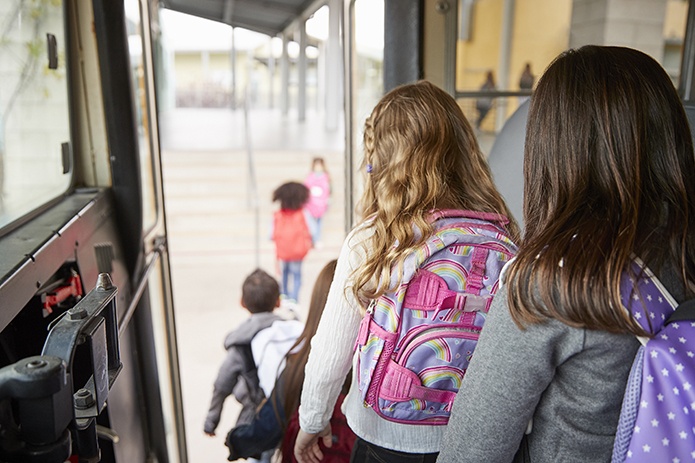 Children with backpacks getting off a school bus