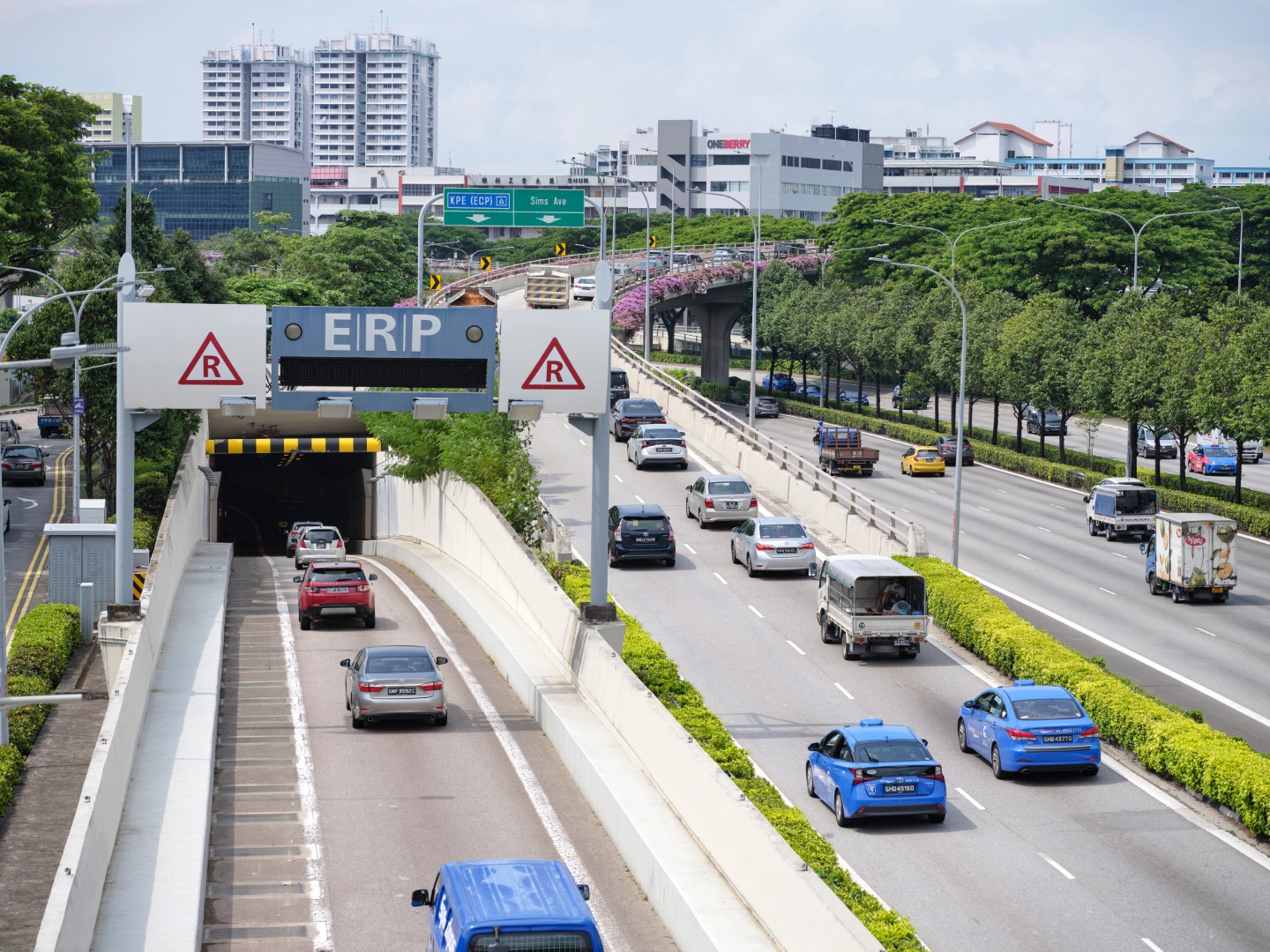 Expressway traffic passing under an ERP road pricing gantry near a tunnel entrance
