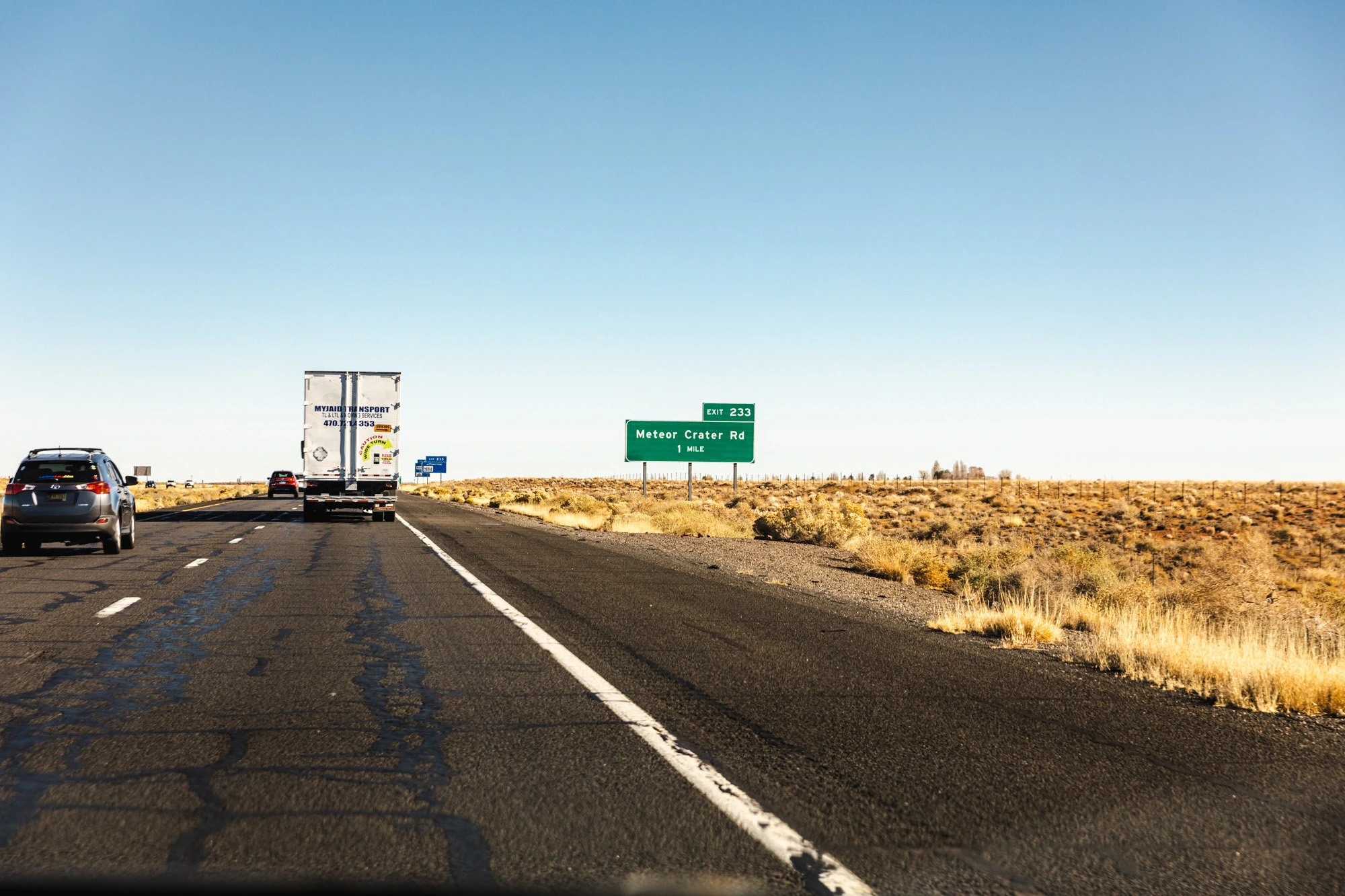 Truck and car on a straight highway through dry grassland